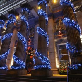 blue holiday lights wrapped around building columns Christmas trees Christmas wreaths