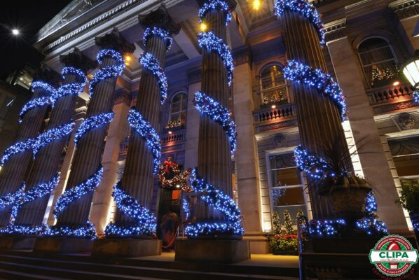 blue holiday lights wrapped around building columns Christmas trees Christmas wreaths