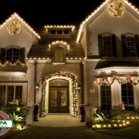 white holiday lights on wreath framing residential home archway balcony