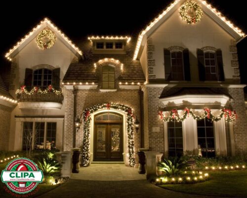 white holiday lights on wreath framing residential home archway balcony