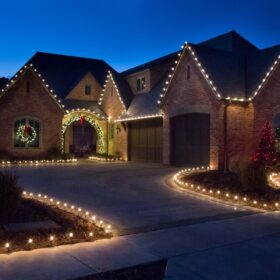 Christmas wreath white holiday lights on wreath framing residential homes archway red holiday lights wrapping trees