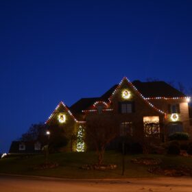 white lights wrapping tree red white holiday lights framing residential home roof
