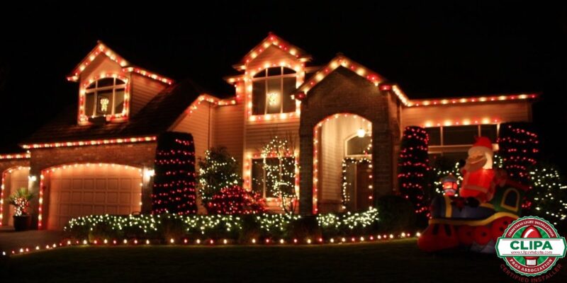 red holiday lights framing residential homes roof bushes archway white holiday lights wrapping trees bushes